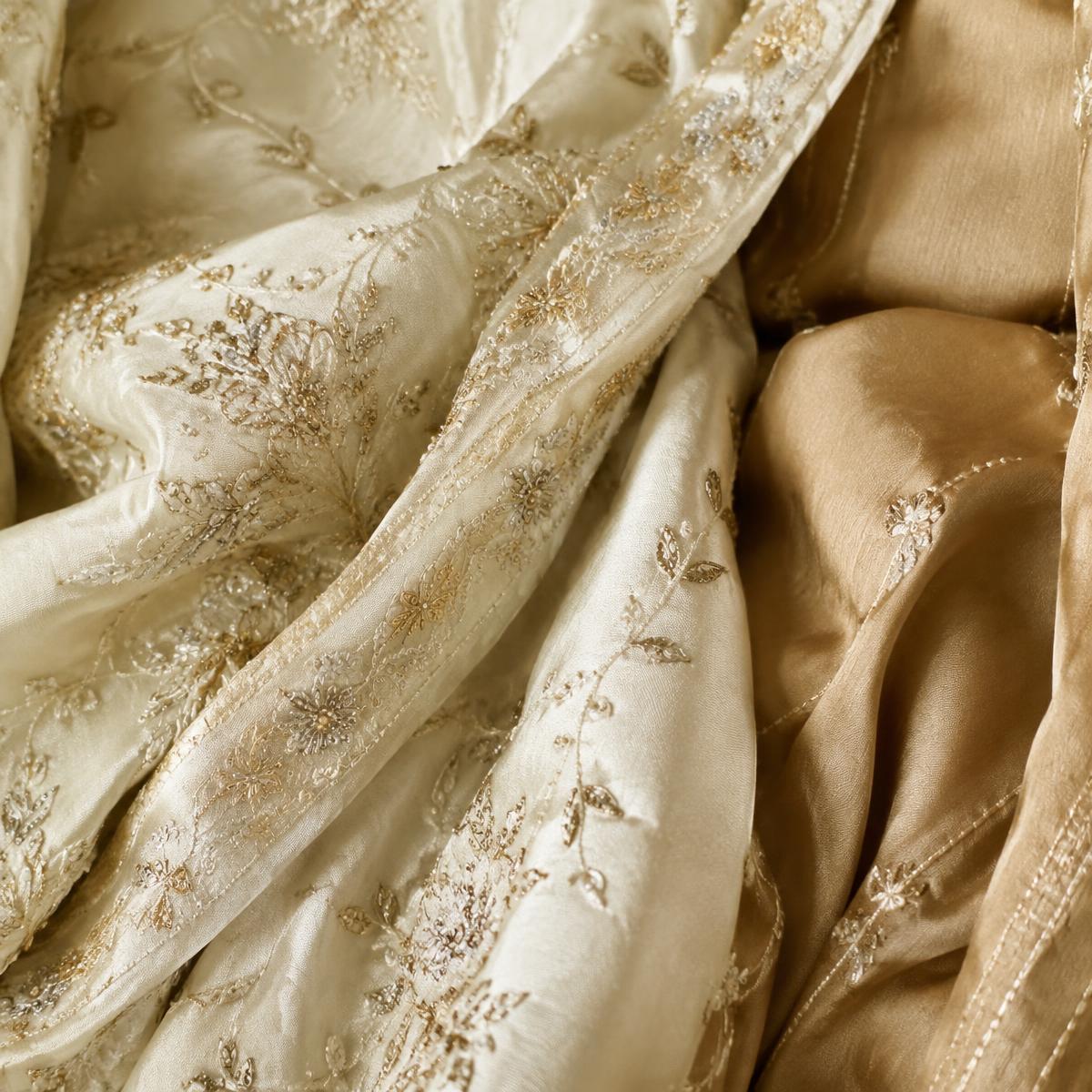 Close-up of ivory and champagne fabric with delicate gold embroidery detail